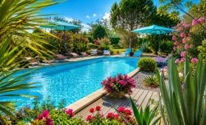 a swimming pool with chairs and umbrellas and flowers at La Lucques Masabelle in Mirepeisset