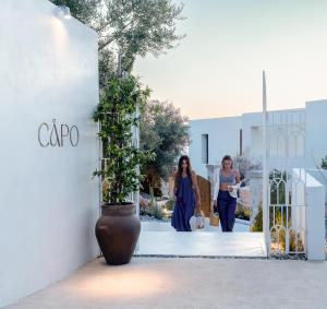 two women walking down a sidewalk in front of a building at CAPO LEFKADA Villa 71 - Sea View - Two Private Pools in Tsoukalades