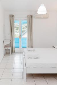 a white bedroom with two beds and a window at Afroditi Pansion in Agios Nikitas +186 photos