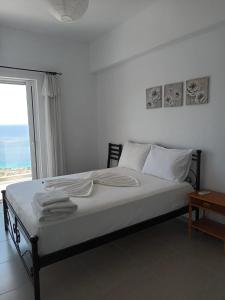a bedroom with a bed with white sheets and a window at Paradise View in Himare