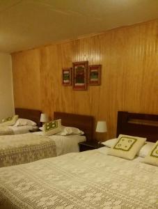 a hotel room with two beds and wooden walls at Apartamento Bordeluna in Coihaique