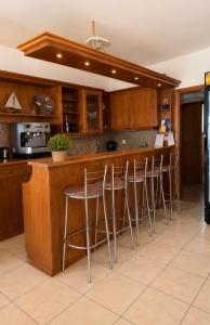 a kitchen with wooden cabinets and a bar with stools at Marialena hotel in Archangelos