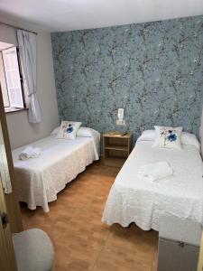 two beds in a room with blue wallpaper at Apartamento Linde in Muros