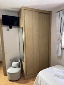 a bedroom with a large wooden cabinet and a chair at Apartamento Linde in Muros