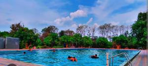 a swimming pool with people in the water at The corbett story in Rāmnagar