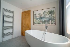 a white bath tub in a bathroom with a picture at St James House Timeless Comfort Central Congleton in Congleton +45 photos