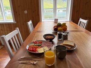 a wooden table with breakfast foods and orange juice at Cozy Home with Breathtaking Mountains and Sea Views in Flateyri