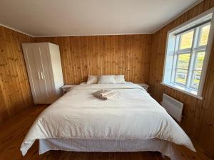 a bedroom with a large white bed with a window at Cozy Home with Breathtaking Mountains and Sea Views in Flateyri