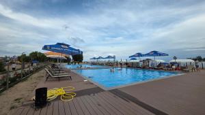 a swimming pool with blue umbrellas and people in it at Cottage on Issyk-Kul, Royal Beach in Chok-Tal