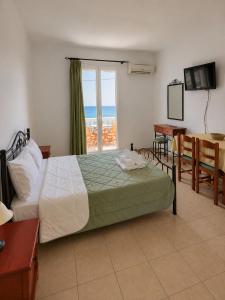 a bedroom with a bed and a desk and a window at Marialena hotel in Archangelos