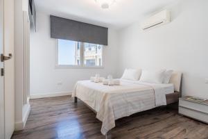 a white bedroom with a large bed and a window at Luxury 2BR Limassol Marina Views in Limassol