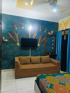 a living room with a couch and a tv on a wall at Crown Valley Guest House in Lahore