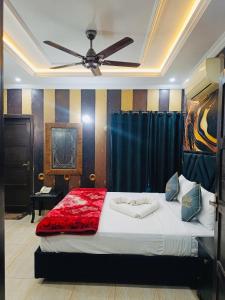 a bedroom with a bed with a ceiling fan at Crown Valley Guest House in Lahore