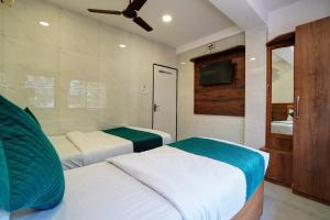 a bedroom with two beds and a tv on the wall at Hotel Benz Inn in Mumbai +53 photos