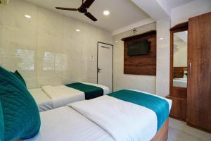 a bedroom with two beds and a tv on the wall at Hotel Benz Inn in Mumbai