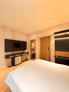 a bedroom with a white bed and a flat screen tv at D'la Lento Hotel in Hanoi