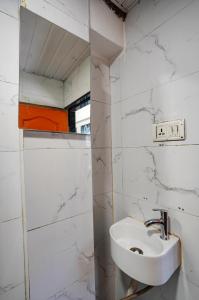 a white bathroom with a sink and a mirror at Hotel Benz Inn in Mumbai