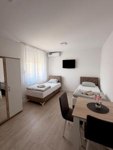 a bedroom with two beds and a table and a dining room at Vila Šarić in Doglodi
