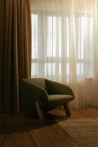 a green chair sitting in front of a window at Horizont Aparthotel Jahorina in Jahorina