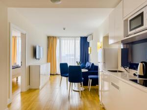 a kitchen and living room with blue chairs in a room at Orbi City Sea View Balcony ApartHotel in Batumi