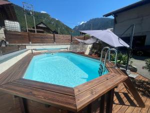 a swimming pool with a wooden deck and an umbrella at Mazot en Abondance in Vacheresse