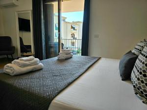 two towels on a bed in a room with a window at Casa Giulia Olbiamare in Olbia