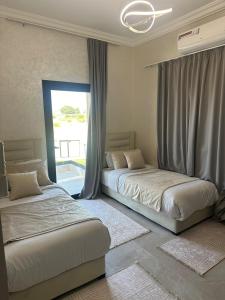 two beds in a room with a window at Villa with pool, ping pong table, trampoline in Mellah Bakka +17 photos