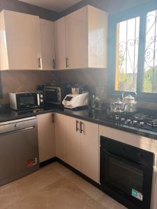 a kitchen with white cabinets and black counter tops at Villa with pool, ping pong table, trampoline in Mellah Bakka
