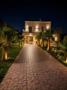 a cobblestone driveway leading to a house at night at Villa with pool, ping pong table, trampoline in Mellah Bakka