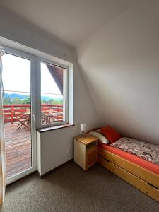 a small bedroom with a bed and a large window at Chalet Parížovce with swimming pool and mountain views in Liptovský Trnovec +29 photos