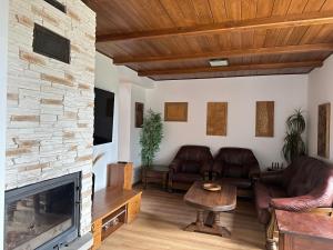 a living room with leather furniture and a stone fireplace at Chalet Parížovce with swimming pool and mountain views in Liptovský Trnovec