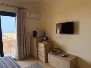 a bedroom with a tv and a bed and a balcony at Art Home - La Hacienda, Ras Sudr in Ras Sedr
