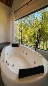 a bath tub in a room with a large window at Rancho do Zé João in Lavrinhas