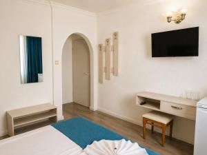 a white room with a bed and a tv on the wall at Guest House Kolev - central in Nesebar
