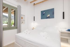 a white bedroom with a bed and a window at À La Plage Residences 03 in Platis Gialos