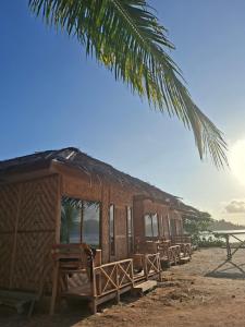 a row of huts on the beach with a palm tree at Batu Mela Cottage in Banggai