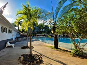a swimming pool with palm trees next to a resort at Au Paradis de Peggy - Bungalow 5 pers - Village de la Pointe Faula in Le Vauclin