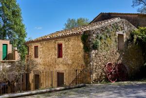 an old stone building with a red wheel on it at Mas Ferrer Petit by 123ole in Sant Andreu del Terri
