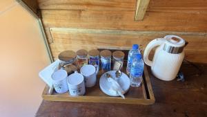 a tray with cups and bottles of water and a kettle at Glenora Wood Cabin in Ella +37 photos