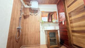 a bathroom with a shower and a wooden wall at Glenora Wood Cabin in Ella