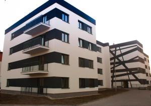 a white building with black balconies next to a building at Apartament Fabryczna Premium TK in Namysłów