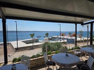 a patio with tables and chairs and the water at Bed and Breakfast MIRAMAR in Starigrad