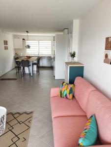 a living room with a pink couch and a kitchen at La terrasse de Bonne terre in Saint-Claude
