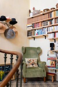 a green chair in a room with bookshelves at Chez ma poule in Moissac