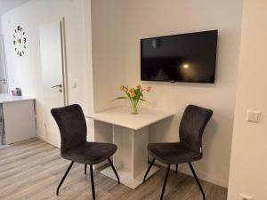 a room with two chairs and a table with a tv at Prime Host Flair Apartment in Karlsruhe
