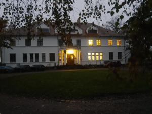 a large white house with its lights on at Ferien am Schloss - Wohnung 2 "die Maus", Ferienwohnung am Badesee in Behren-Lübchin