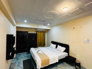 a bedroom with a bed and a television in it at The Aura Grand Hotel and Cafe in Patna