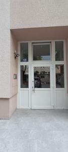 a white door of a building with a man standing outside at Apartman Sandra in Varaždin