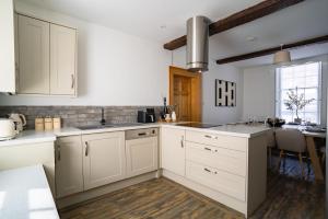 a white kitchen with white cabinets and a table at St James House Timeless Comfort Central Congleton in Congleton