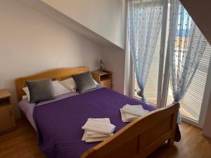 a bedroom with a purple bed and a large window at Guest House Lav in Primošten